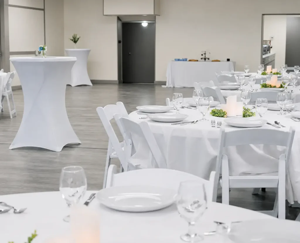 Reception space arranged with white tables, chairs, place settings, and cocktail tables at The Hostetler Event Venue in Downtown Decatur IL.